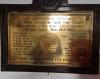 Brass plaque mounted on wooden board