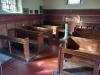 Wooden pews in stone church showing memorial engraving
