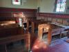 Wooden pews in stone church showing memorial engraving