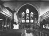Pre-WW2 image of the church, showing the reredos behind the altar, and the three dedicatory panels in the side-aisle on the left