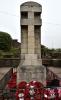Memorial stone pillar surrounded by a low wrought iron railing.
